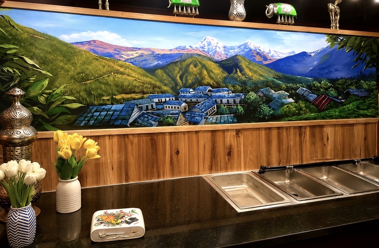 Panoramic mountain village mural installed above a restaurant service counter